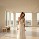 Woman in a white wedding dress standing on a beach with ocean in the background