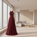 Woman wearing a burgundy evening gown with a sequined top in a store setting.