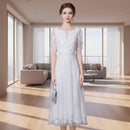 Woman wearing a white lace dress against a gray background